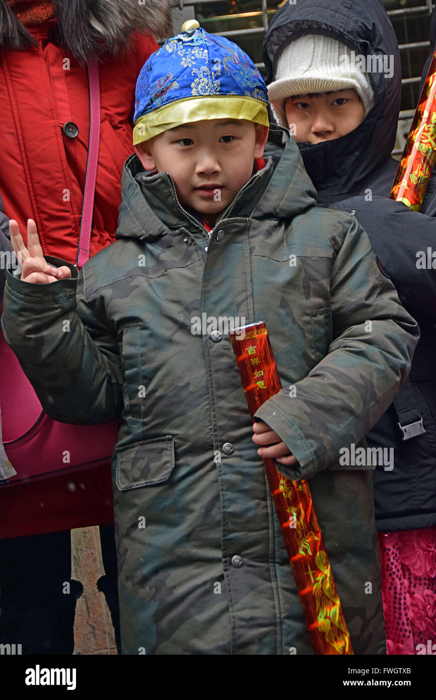 Un giovane americano asiatico lad fa un segno di pace mentre al Capodanno cinese anni sfilano su Mott Street a Chinatown, il centro cittadino di New York. Foto Stock
