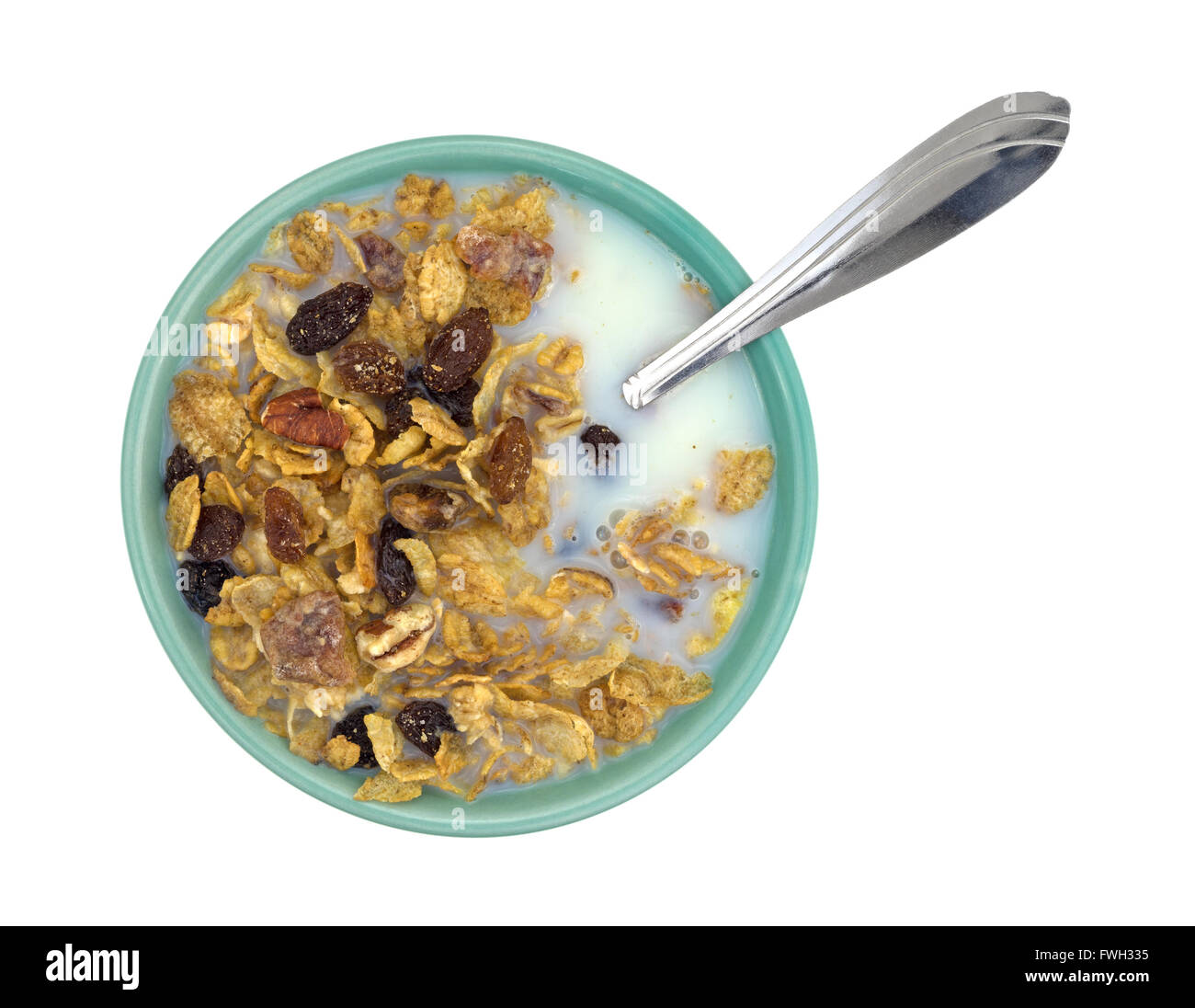 Vista dall'alto di una tazza di noci pecan, uvetta e date prima colazione a base di cereali con latte scremato plus cucchiaio isolato su uno sfondo bianco. Foto Stock