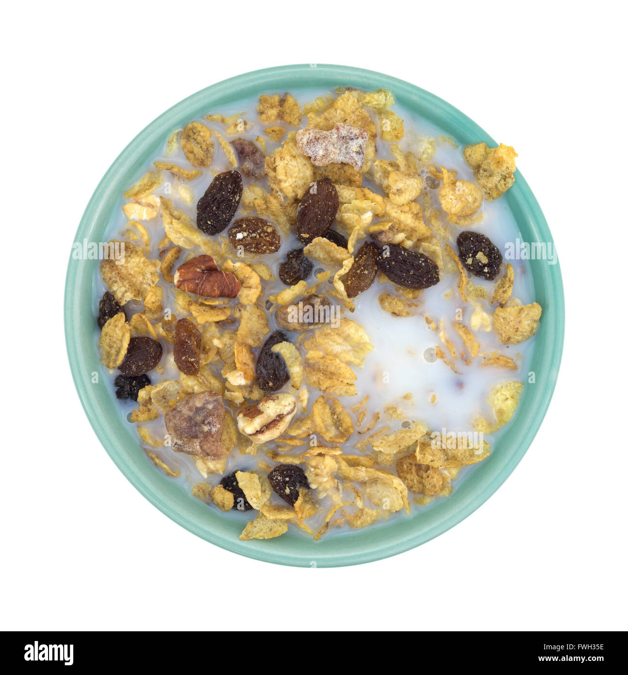 Vista dall'alto di una tazza di noci pecan, uvetta e date prima colazione a base di cereali con latte scremato isolato su uno sfondo bianco. Foto Stock