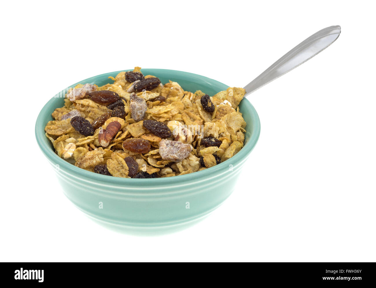 Vista laterale di un vaso riempito con le noci pecan, uvetta e date in cereali per la prima colazione con un cucchiaio isolato su uno sfondo bianco. Foto Stock
