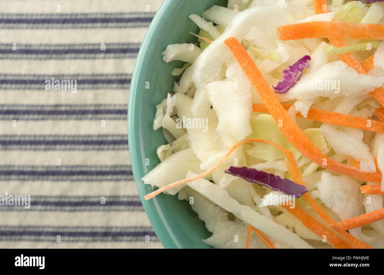 Top vista ravvicinata di una ciotola riempita con coleslaw su una tovaglia a righe. Foto Stock