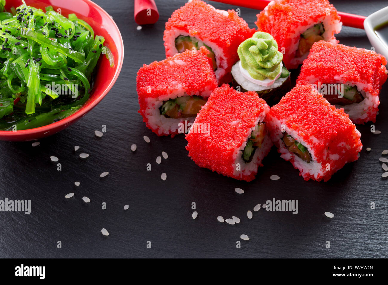 Rotoli di sushi con seasalad verde su una tavola di ardesia. Foto Stock