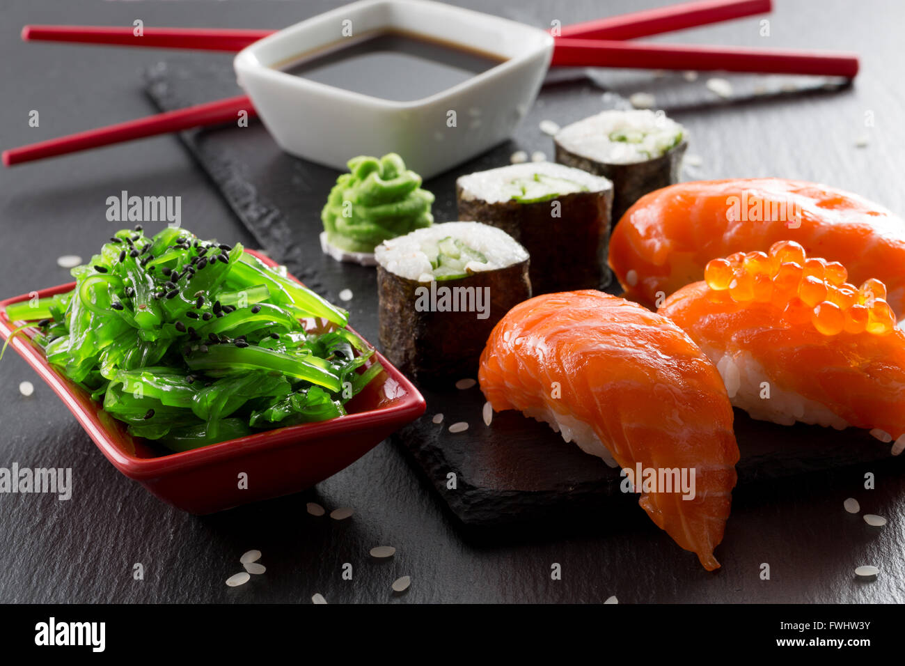 Il sushi e panini con seasalad verde su una tavola di ardesia. Foto Stock