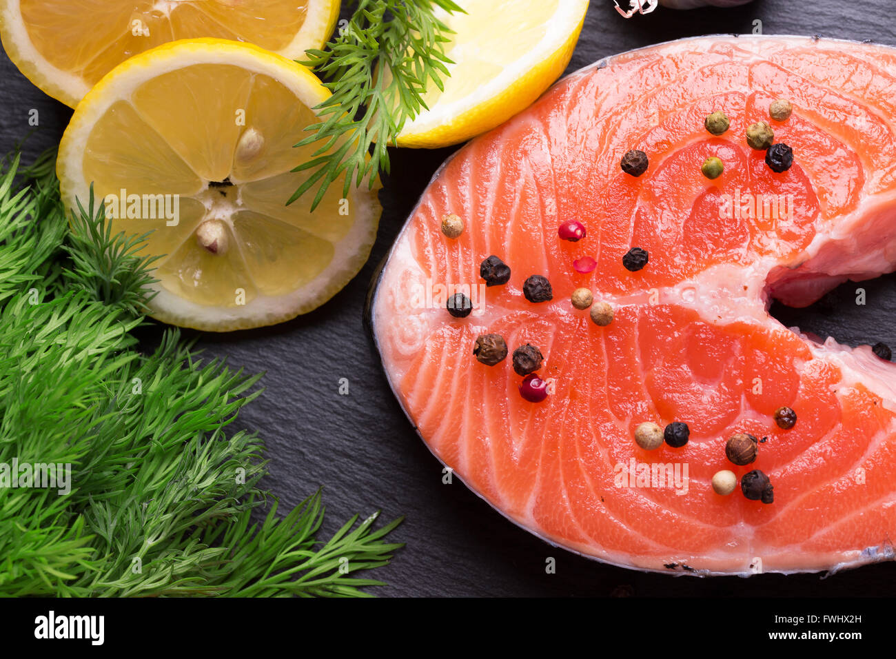 Pesce rosso bistecca con limoni su una tavola di ardesia. Foto Stock