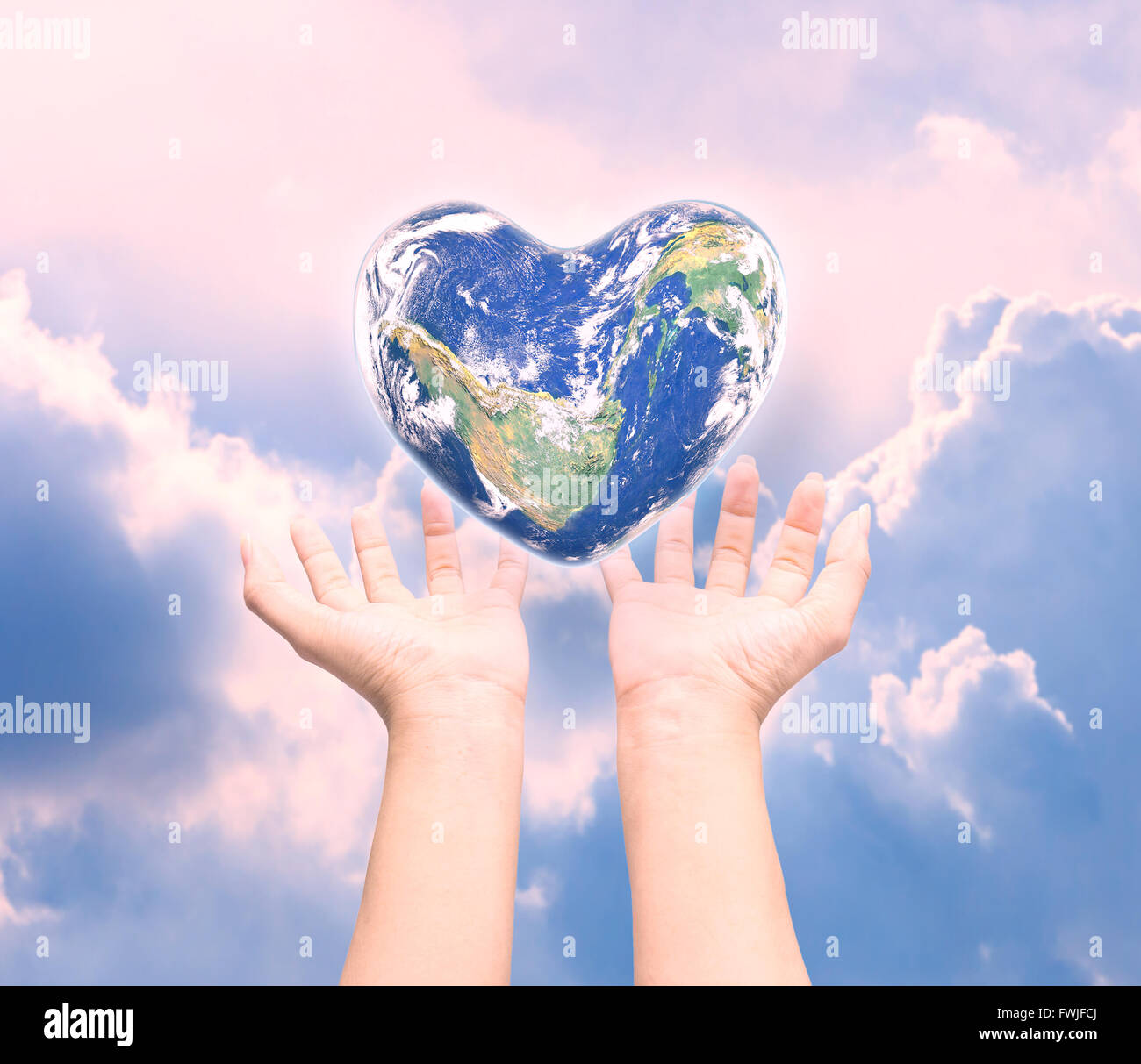 Mondo in forma di cuore con sopra le donne le mani umane su sfocato sfondo naturale: Mondo Salute del cuore giorno,Elemento di questa immagine fur Foto Stock
