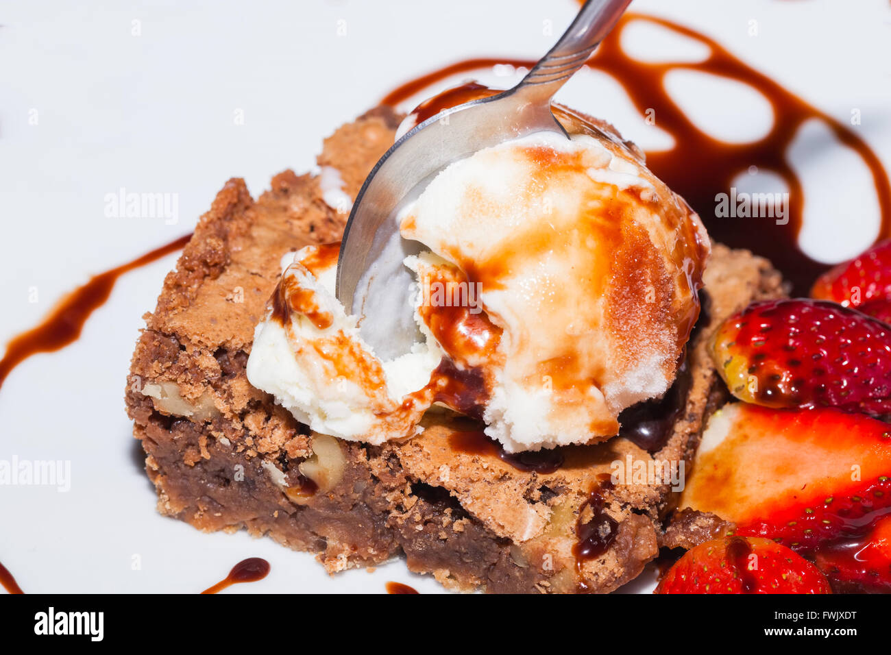 Cucchiaio bloccato in brownie con gelato e fragola, deliziosi dessert Foto Stock