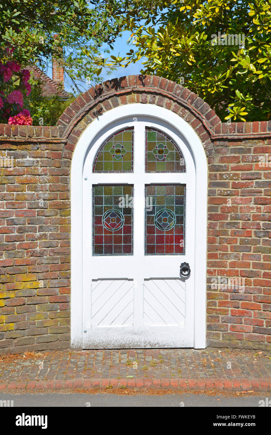 Round top porta con vetro istoriato riquadri di mattoni esterni giardino muro di confine che si apre direttamente sulla pavimentazione pubblica England Regno Unito Foto Stock