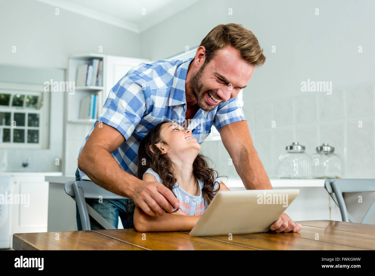 Allegro padre e figlia con tavoletta digitale a tavola Foto Stock