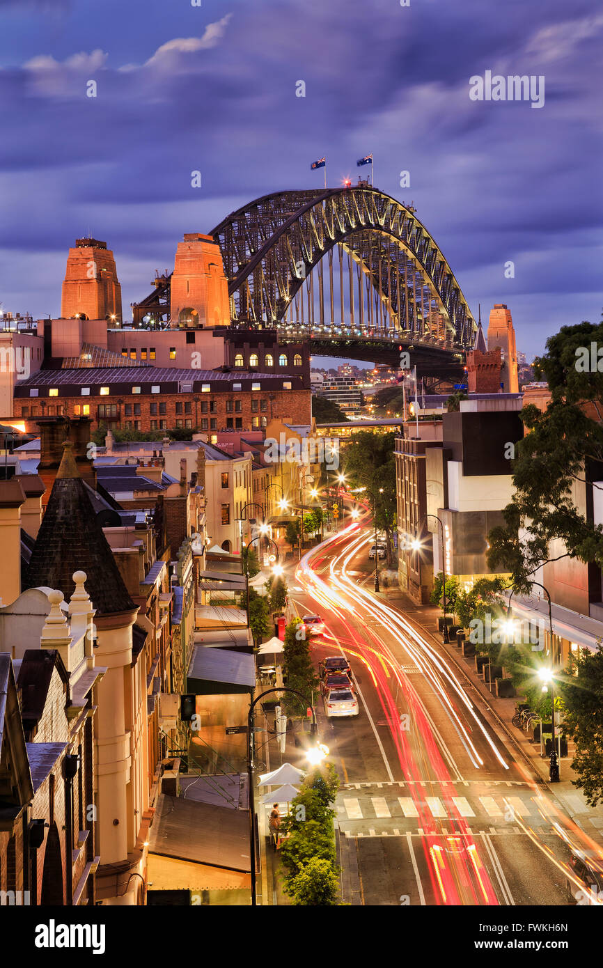 Vista verticale su George Street nelle rocce, Sydney, al tramonto quando luci luminose illumnate la strada , negozi e persone. Foto Stock