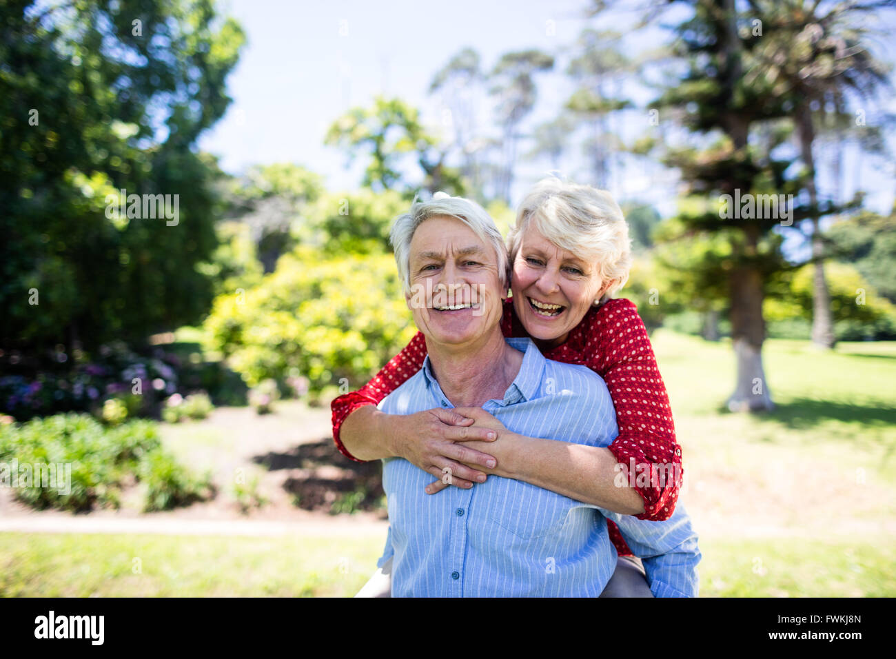 Felice l'uomo senior dando una piggy back per senior donna Foto Stock