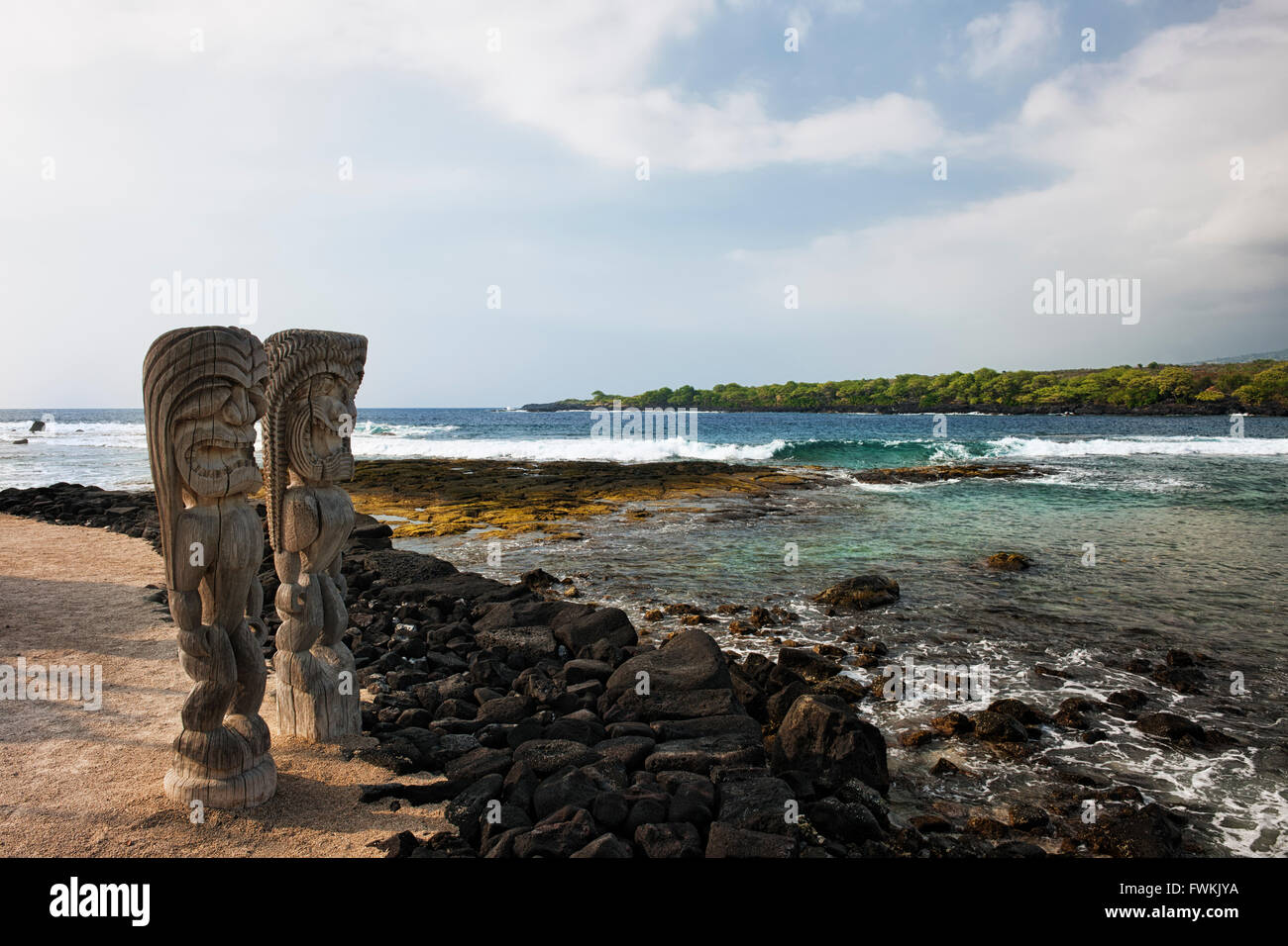 Feroce Ki' mi statue stand guard affacciato sulla Baia di Honaunau presso il luogo di rifugio sulla Big Island delle Hawaii. Foto Stock