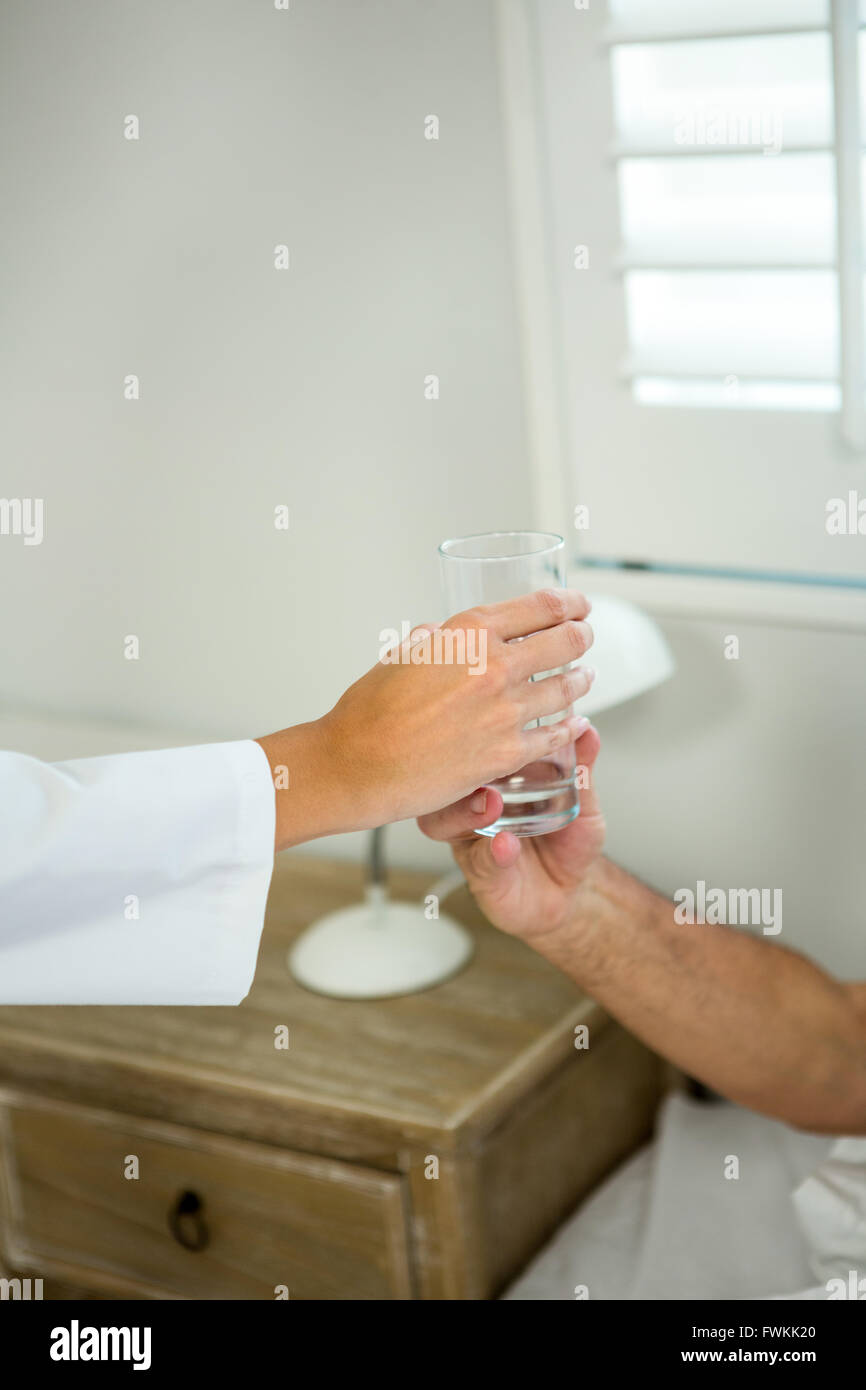 Immagine ritagliata di medico che danno acqua al paziente senior Foto Stock
