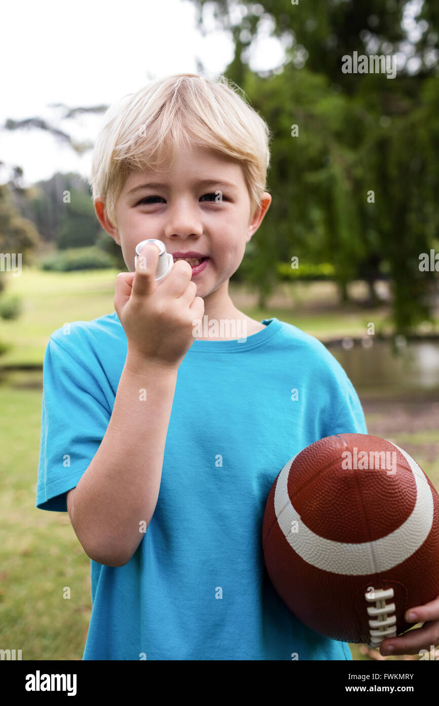 Ragazzo con un calcio americano usando un inalatore per asmatici Foto Stock