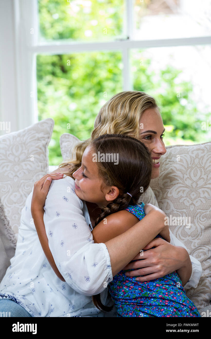 Felice madre e figlia abbracciando sul divano Foto Stock