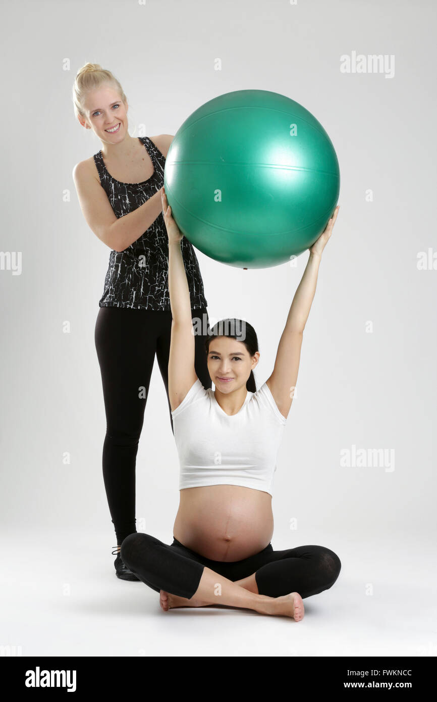 Donna incinta facendo esercizio di fitness con personal trainer Foto Stock