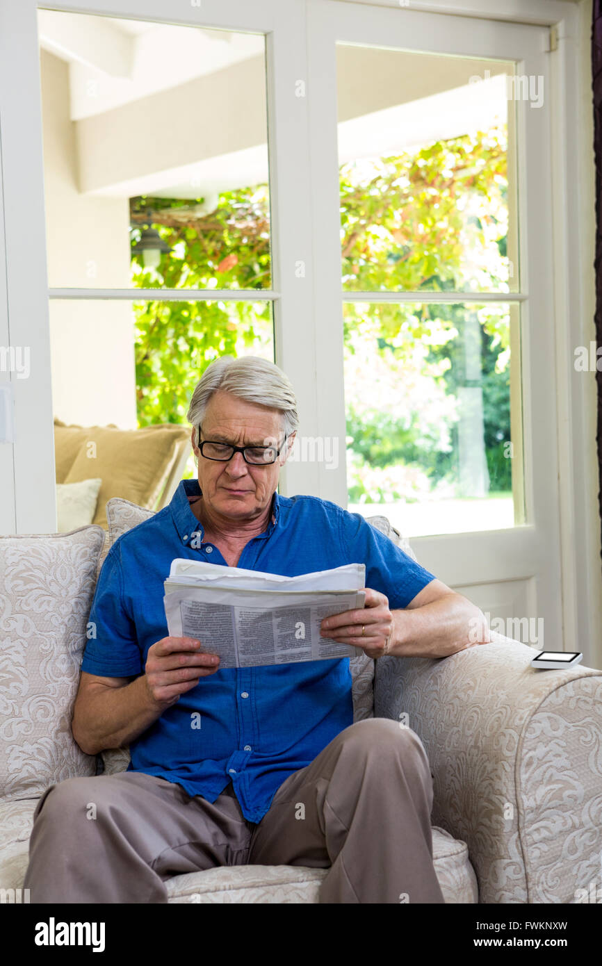 Senior uomo che legge il giornale mentre è seduto a casa Foto Stock