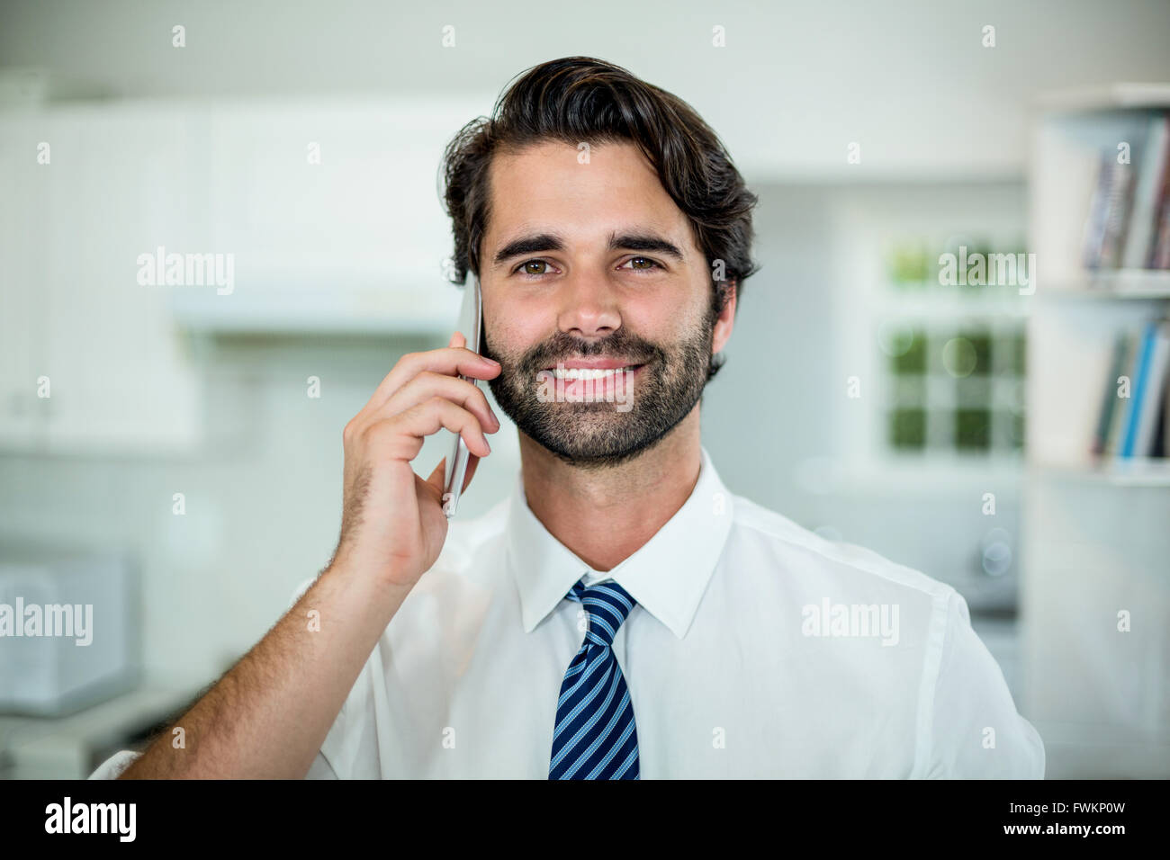 Fiducioso imprenditore parlando al cellulare in cucina Foto Stock