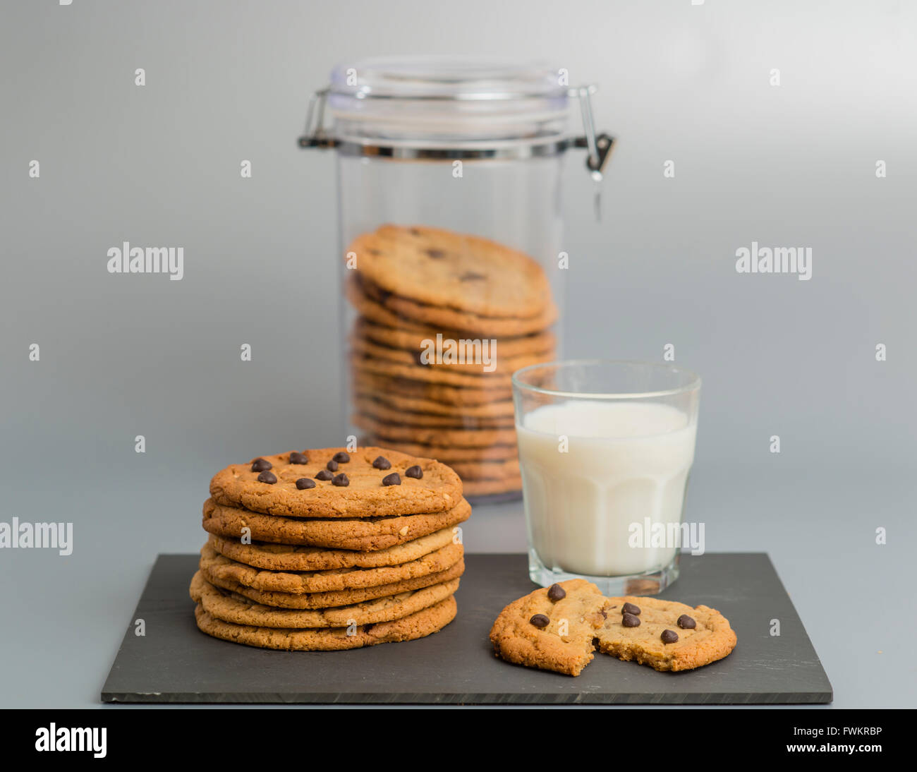 Ancora vita immagine del cookie cookie jar e bicchiere di latte su sfondo grigio. Foto Stock