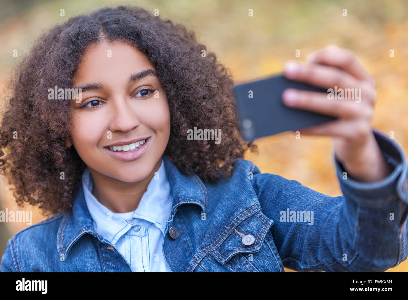 Bella felice razza mista americano africano donna giovane ragazza adolescente femmina perfetta sorridente denti tenendo il telefono cellulare selfie Foto Stock