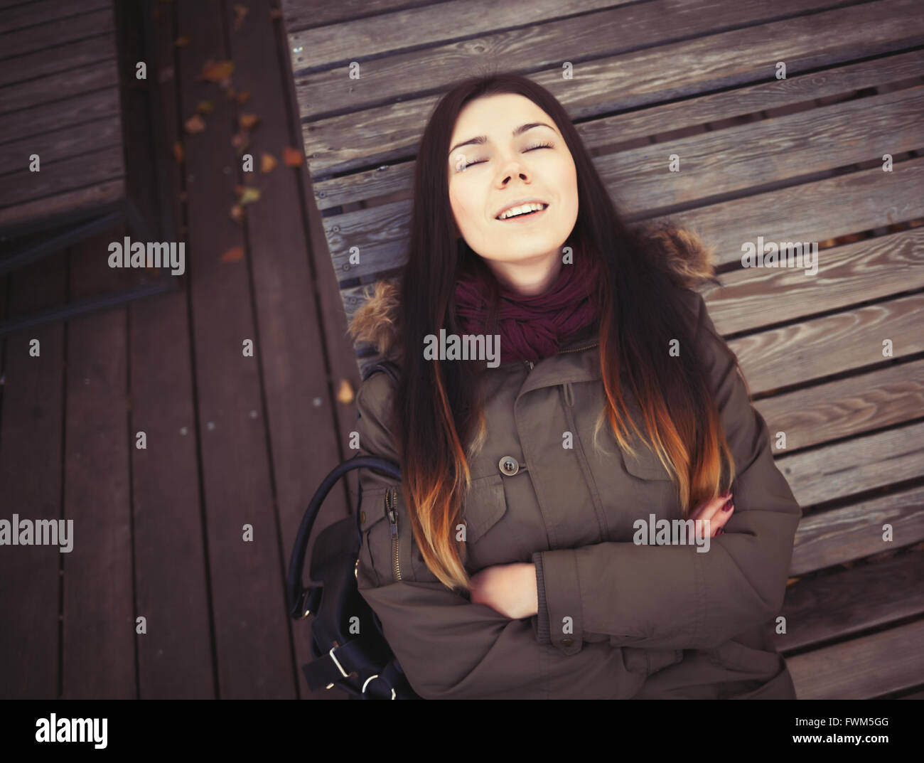 Ritratto di giovane ragazza hipster indossando giacca grigio cappotto e marsala sciarpa giacente in calma su un banco di lavoro. Buon umore, felice espressione facciale Foto Stock