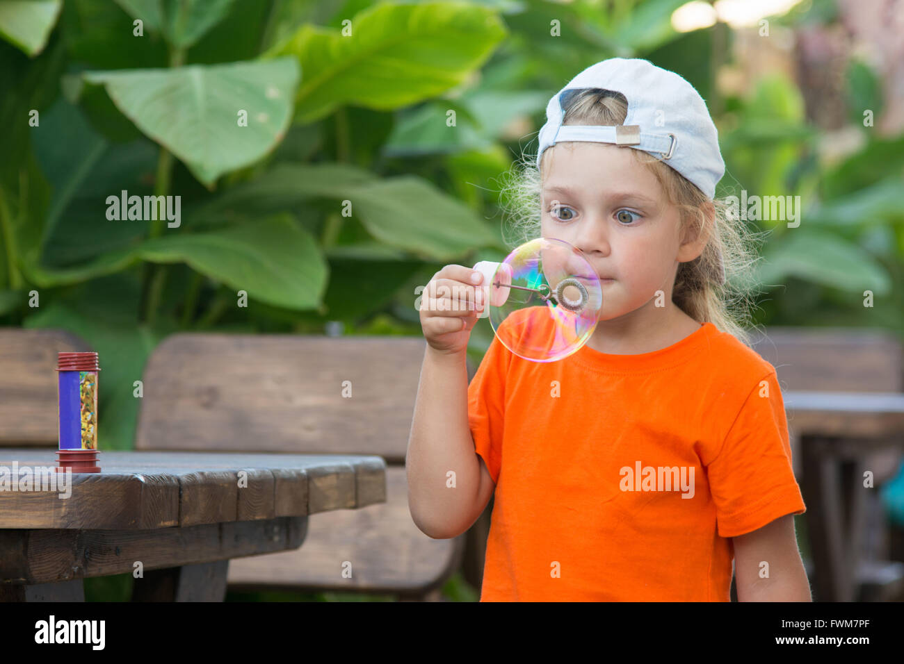 Bambina in una luminosa T-shirt gonfia grande bolla in strada Foto Stock
