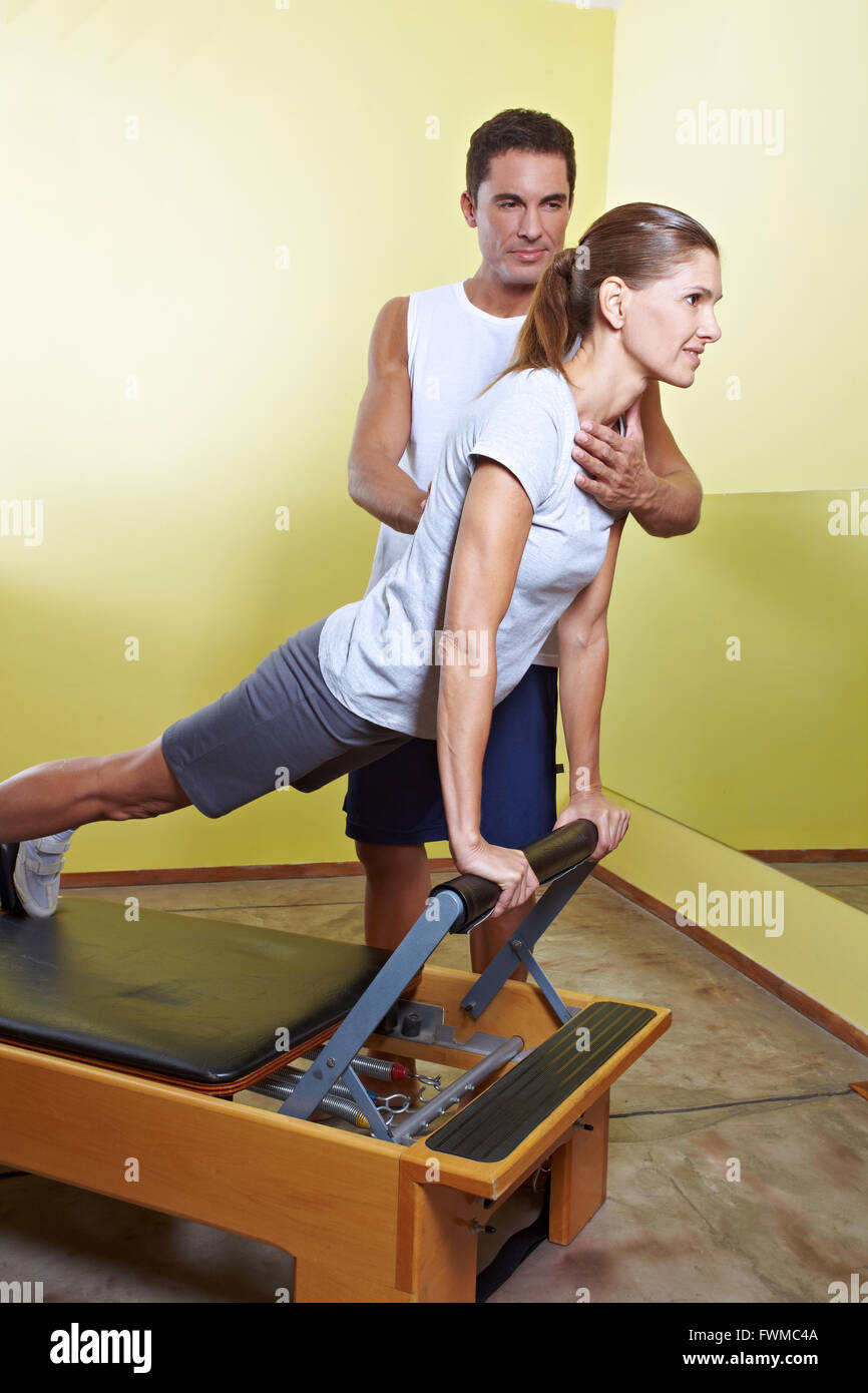Trainer aiutando donna con correzione della postura nel centro fitness Foto Stock