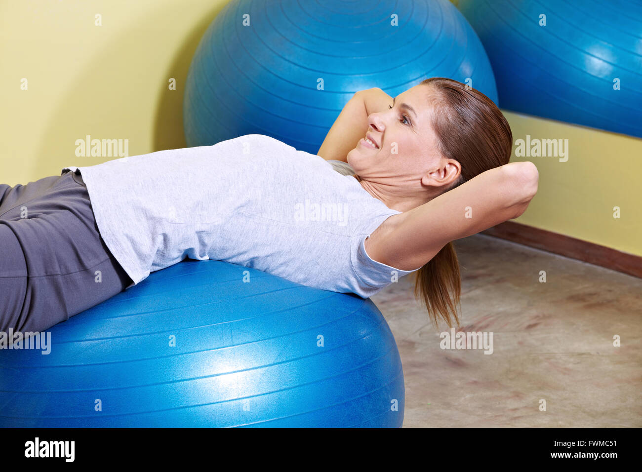 Donna facendo sit ups sulla palla nel centro fitness Foto Stock