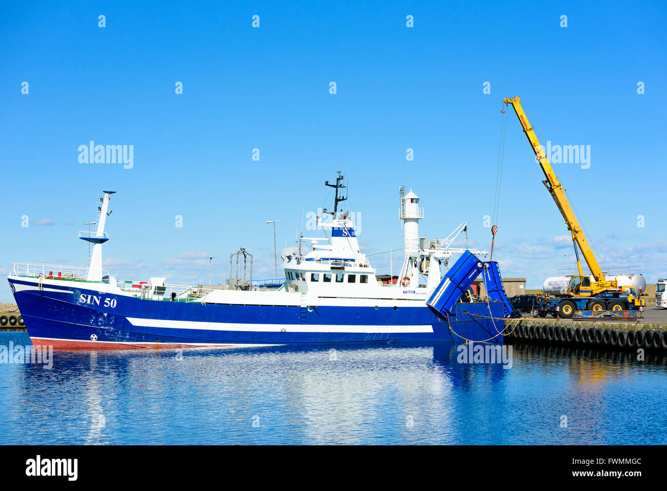 Simrishamn, Svezia - Aprile 1, 2016: Giallo Liebherr Gru mobile di sollevamento di un peschereccio da traino Blu wing dal suolo alla porta. Il lavoro normale Foto Stock