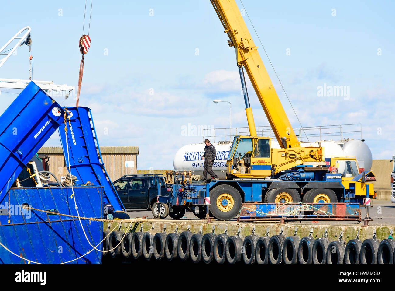 Simrishamn, Svezia - Aprile 1, 2016: Giallo Liebherr Gru mobile di sollevamento di un peschereccio da traino Blu wing dal suolo alla porta. Il lavoro normale Foto Stock