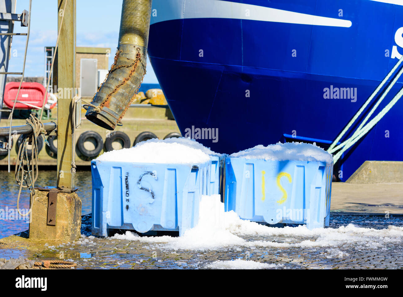 Casse di plastica riempito di ghiaccio freddo per l'uso nell'industria della pesca. Parte di una barca da pesca in background. Un tubo per fillin Foto Stock