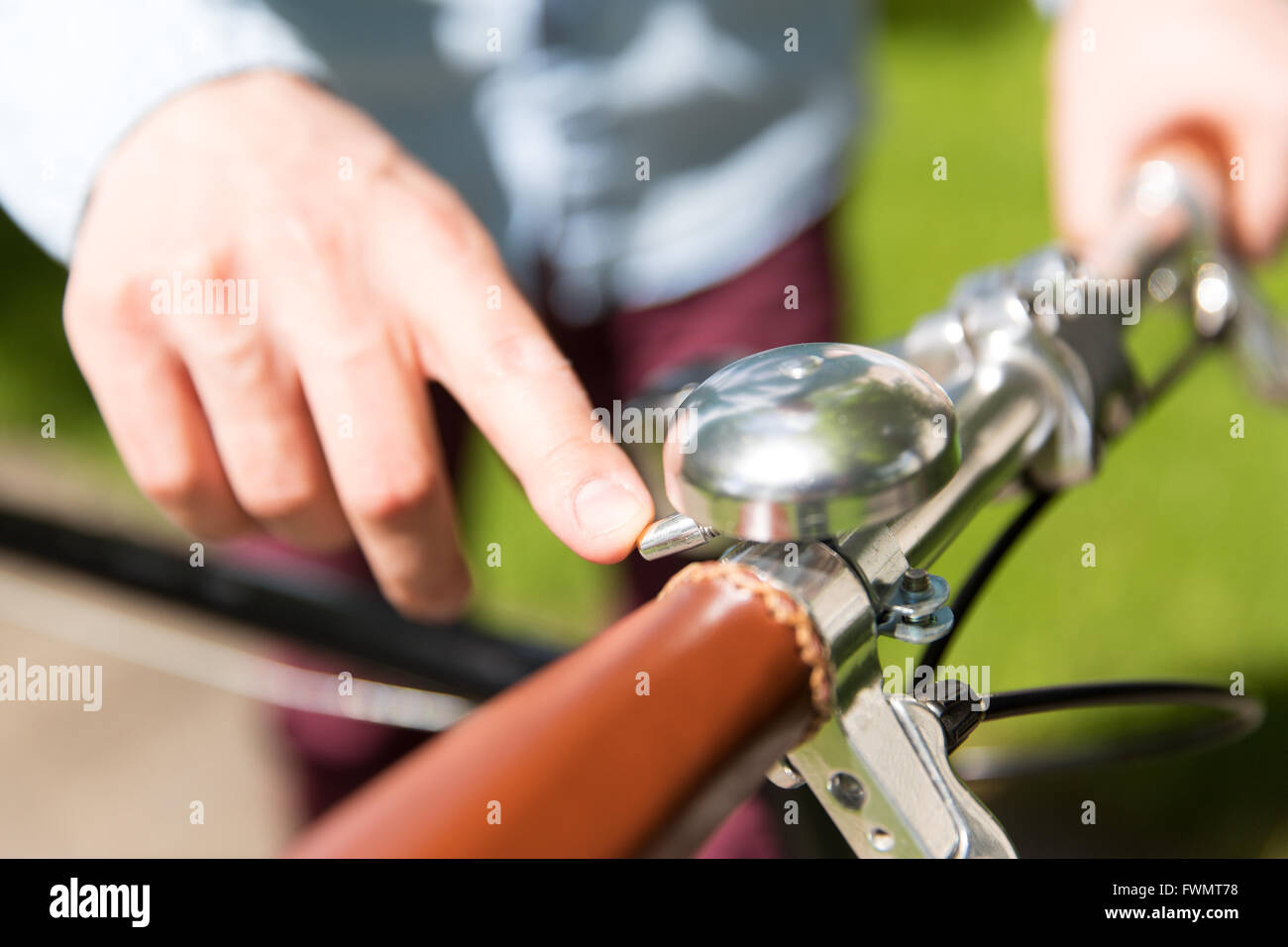 Stretta di mano maschio squillando campana sulla ruota di bicicletta Foto Stock
