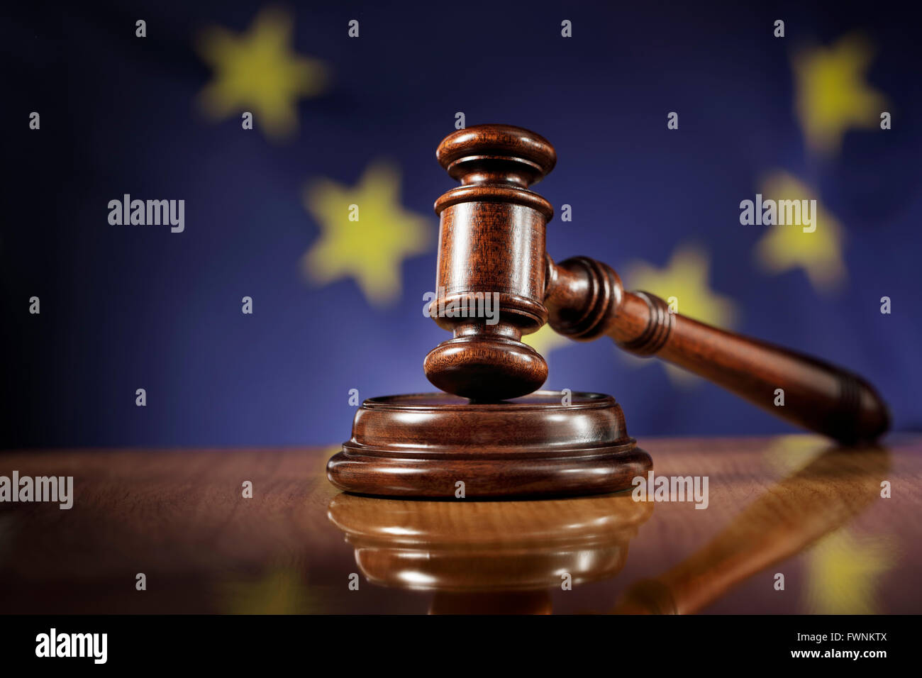 In legno di mogano martello sul lucido tavolo in legno. Bandiera dell'Unione europea, Unione europea, in background. Foto Stock
