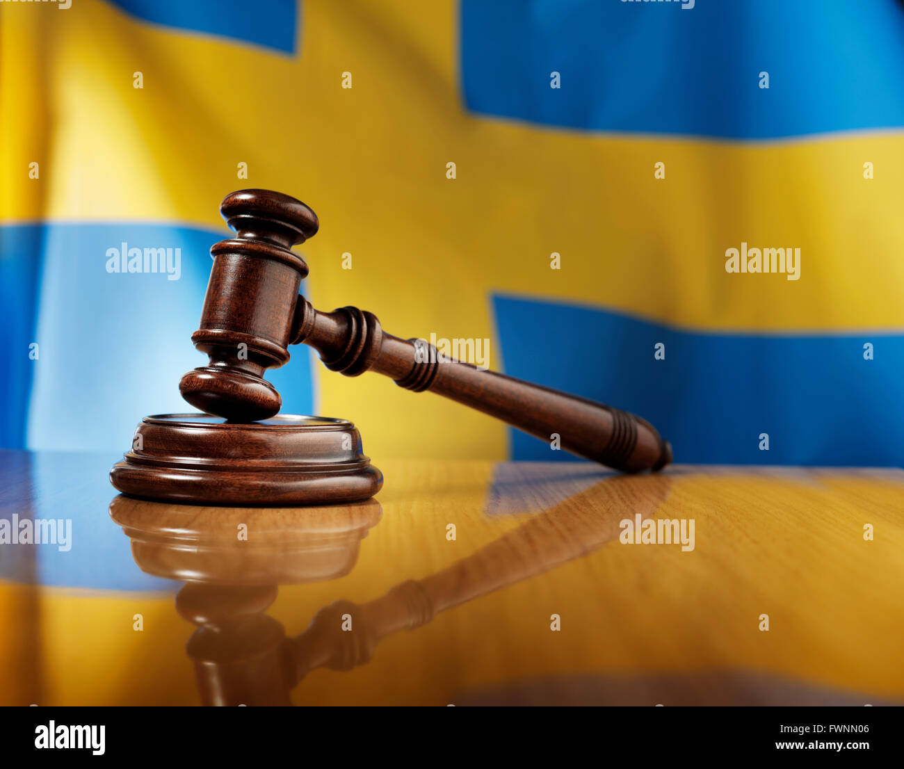 In legno di mogano martello sul lucido tavolo in legno, bandiera della Svezia in background. Foto Stock