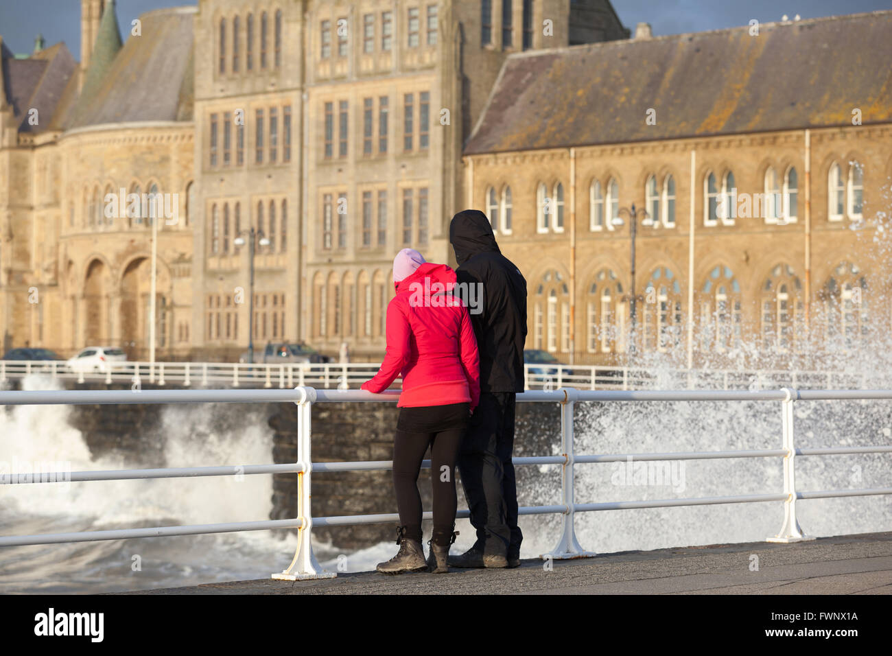 L uomo e la donna in piedi lungo la promenade guardando le onde splash contro le pareti Credito: Ian Jones/Alamy Live News Foto Stock