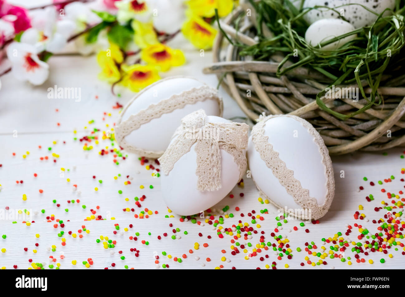 Bellissimo sfondo di Pasqua con i fiori e il nido con le uova dipinte di bianco boards Foto Stock