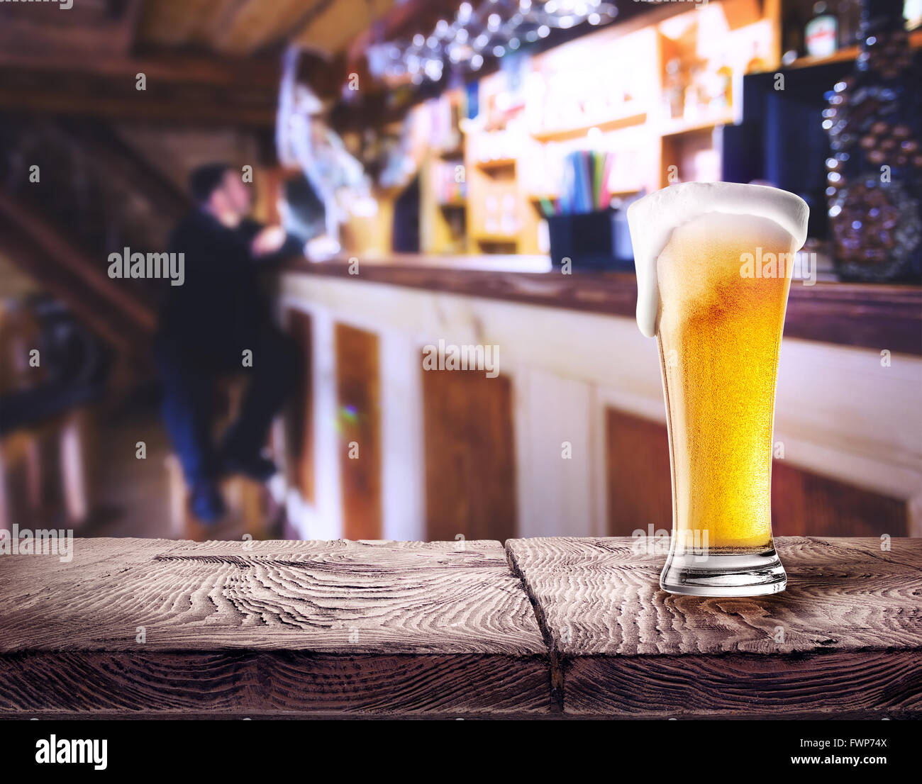 Bicchiere di birra con la schiuma su un tavolo di legno in sfondo della barra Foto Stock