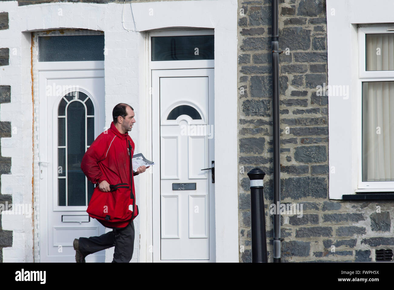 Un postino consegna la posta lettere e mail, Wales UK Foto Stock