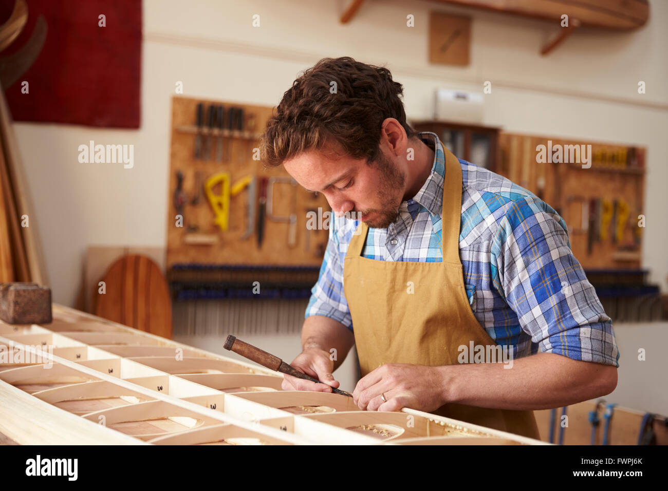 L'uomo edificio in legno su misura con la tavola da surf in officina Foto Stock