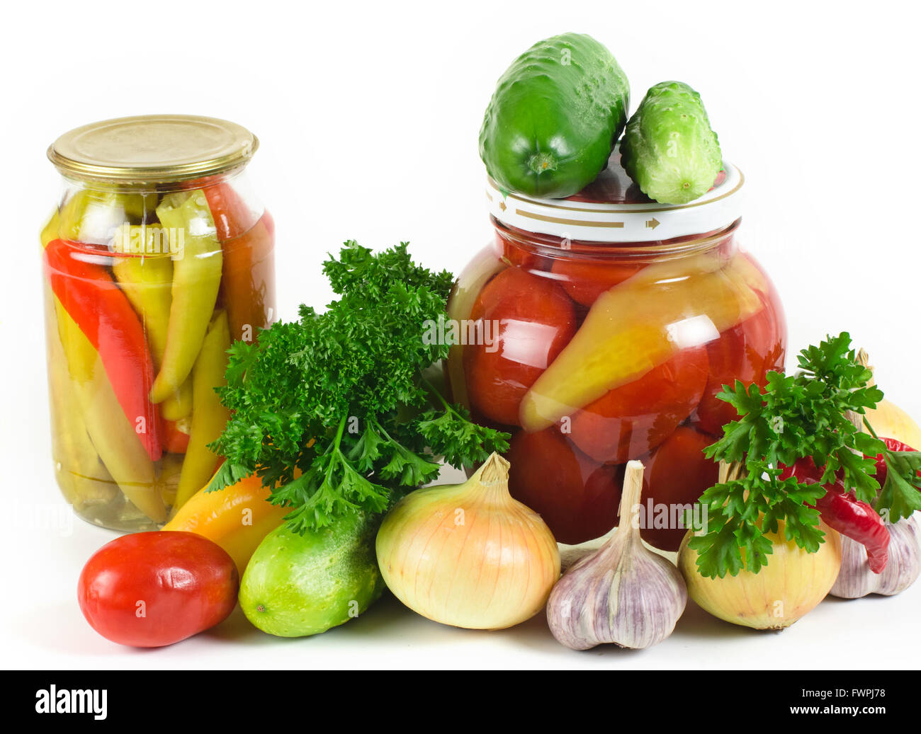 Cipolle, aglio cetrioli e pomodori e prezzemolo giacciono su di una superficie di luce. Una fila di due banche con le conserve di verdura Foto Stock