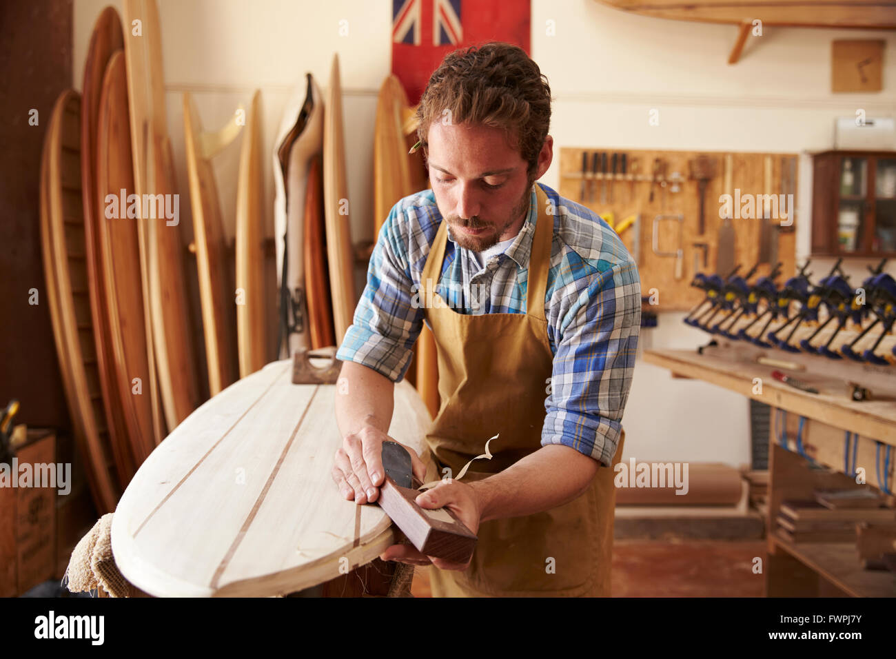 Falegname piallatura di legno su misura con la tavola da surf in officina Foto Stock