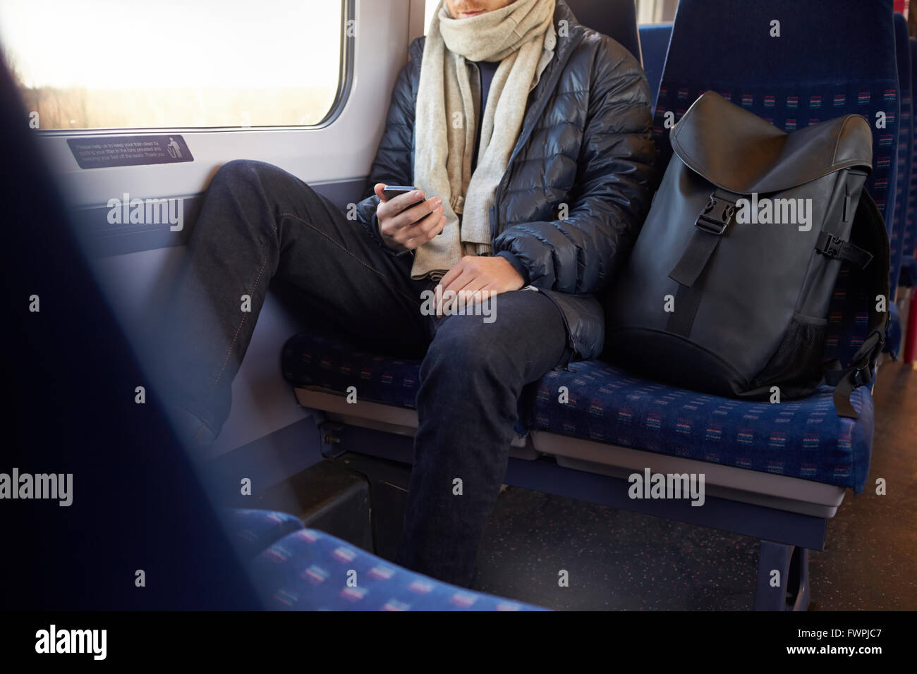 Uomo seduto in treno il trasporto di inviare un messaggio di testo Foto Stock