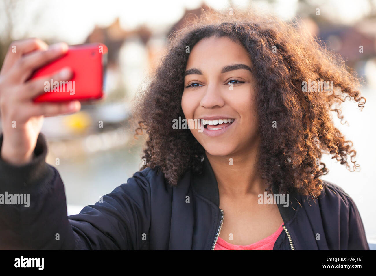 Bella felice razza mista americano africano donna giovane ragazza adolescente sorridente femmina con denti perfetti tenendo selfie fotografia Foto Stock