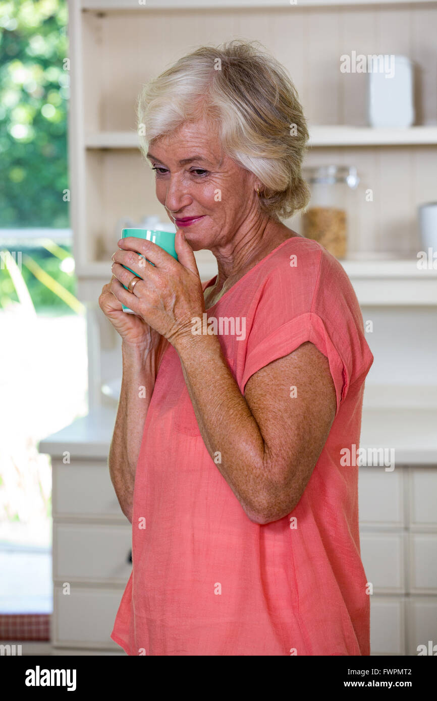 Riflessivo senior donna con caffè in cucina Foto Stock