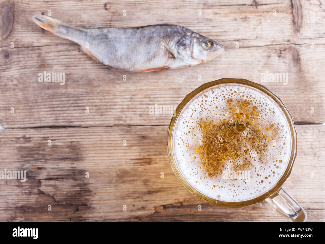 Birra e uno di pesce sulla tavola di legno vista da sopra lo sfondo Foto Stock