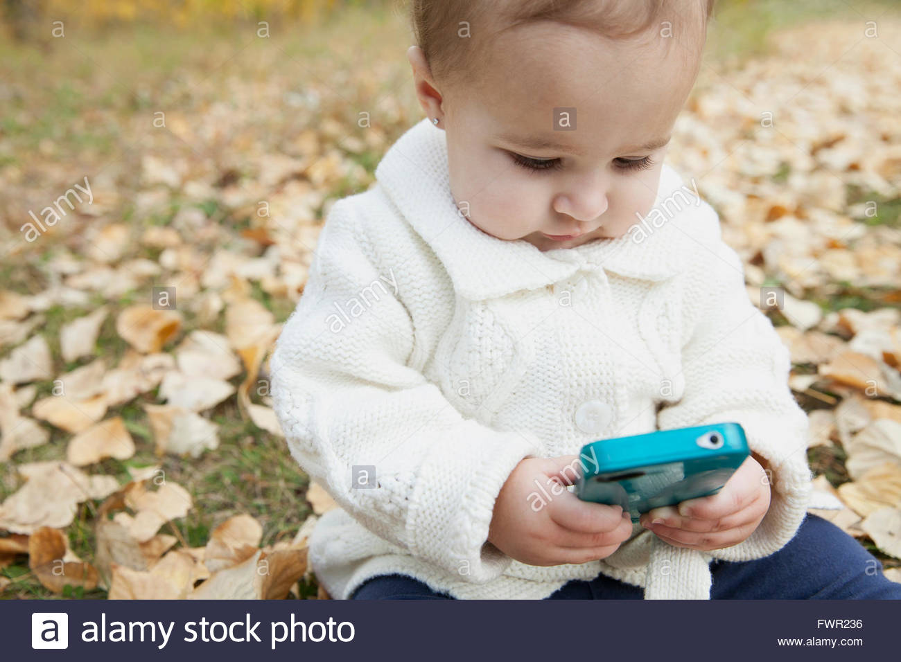 Baby girl giocare con il telefono cellulare in posizione di parcheggio Foto Stock