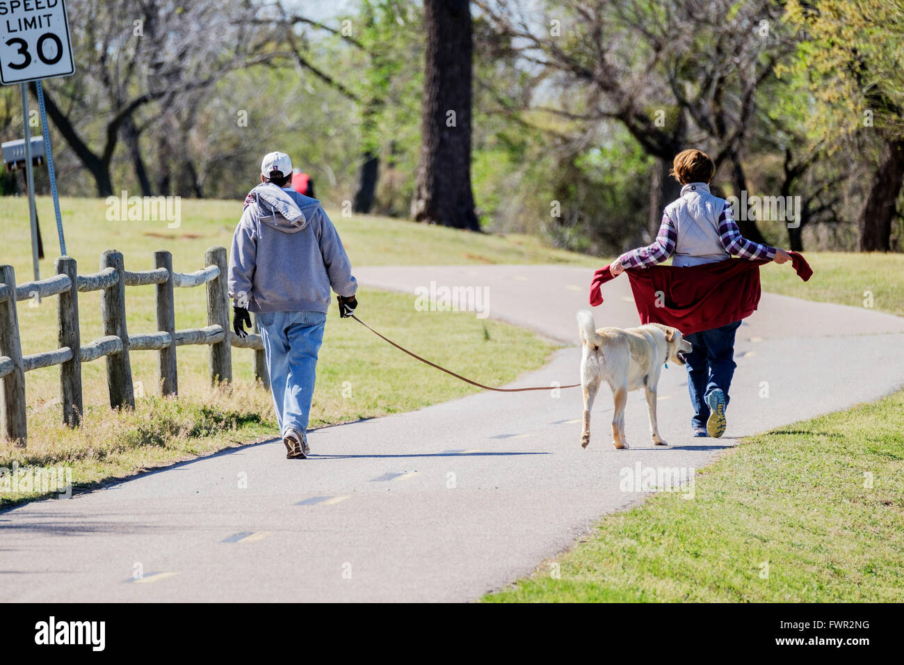 Un uomo e una donna a piedi i sentieri con il loro cane legato al lago Overholser, Oklahoma City, Oklahoma, Stati Uniti d'America. Foto Stock