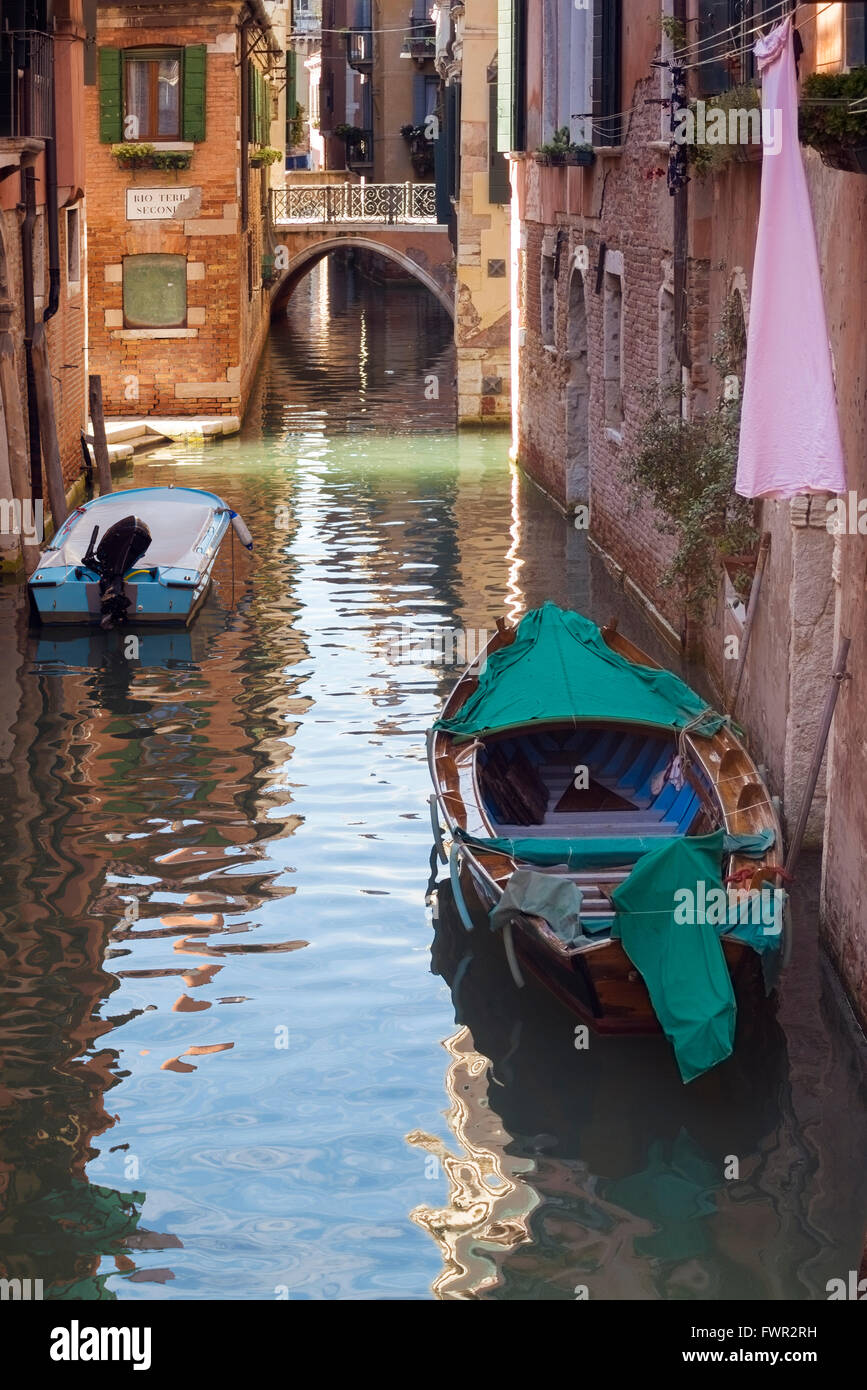 Scena di strada da Venezia con il canale dell'acqua e la vecchia barca di legno in primo piano Foto Stock