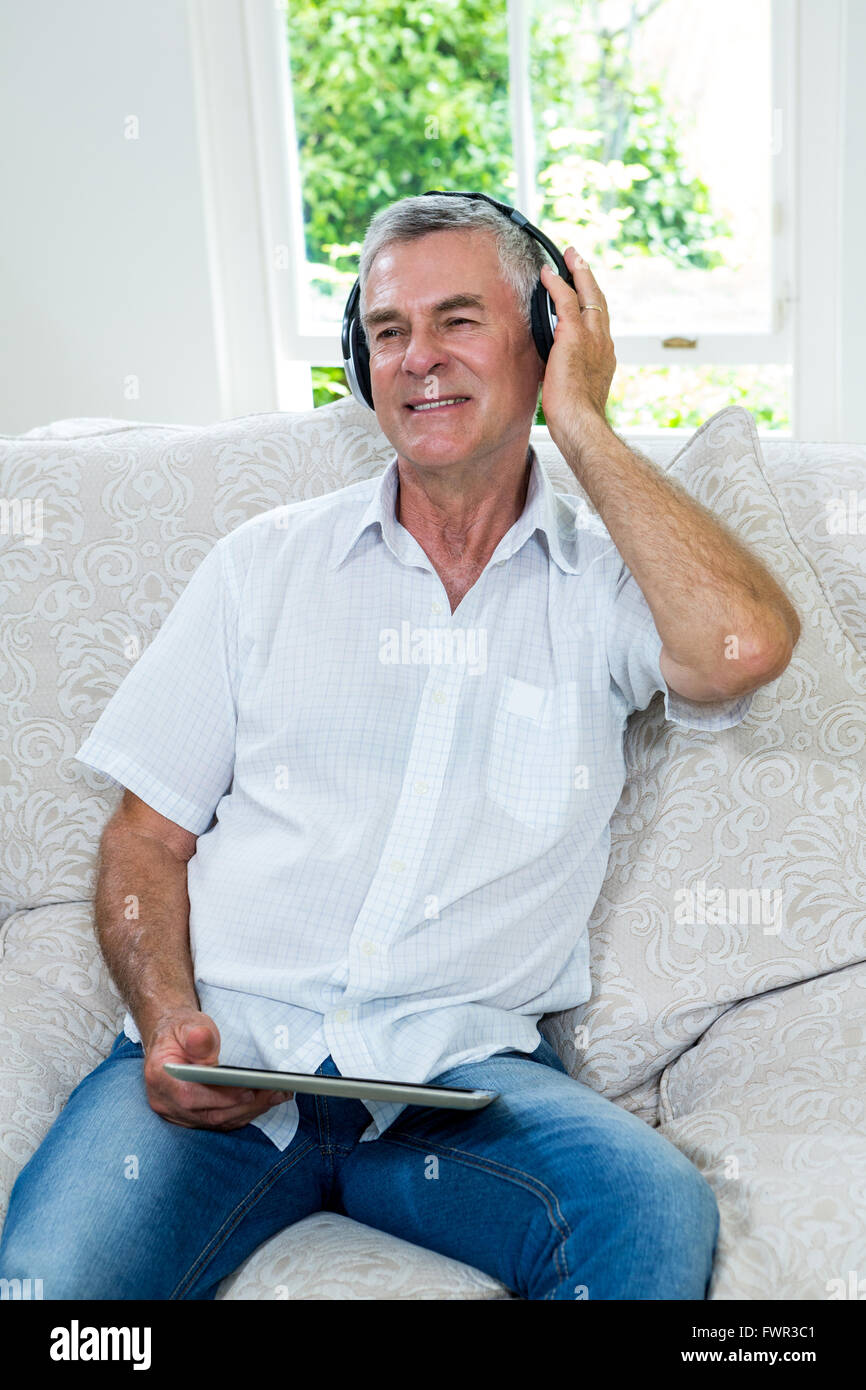 Felice l'uomo senior ascoltando musica in salotto Foto Stock
