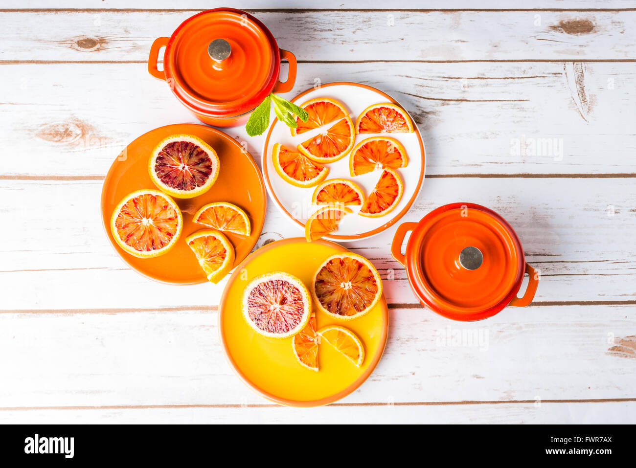 Arance sanguigne affettato su piastre con orange ghisa pentole in legno bianco Foto Stock