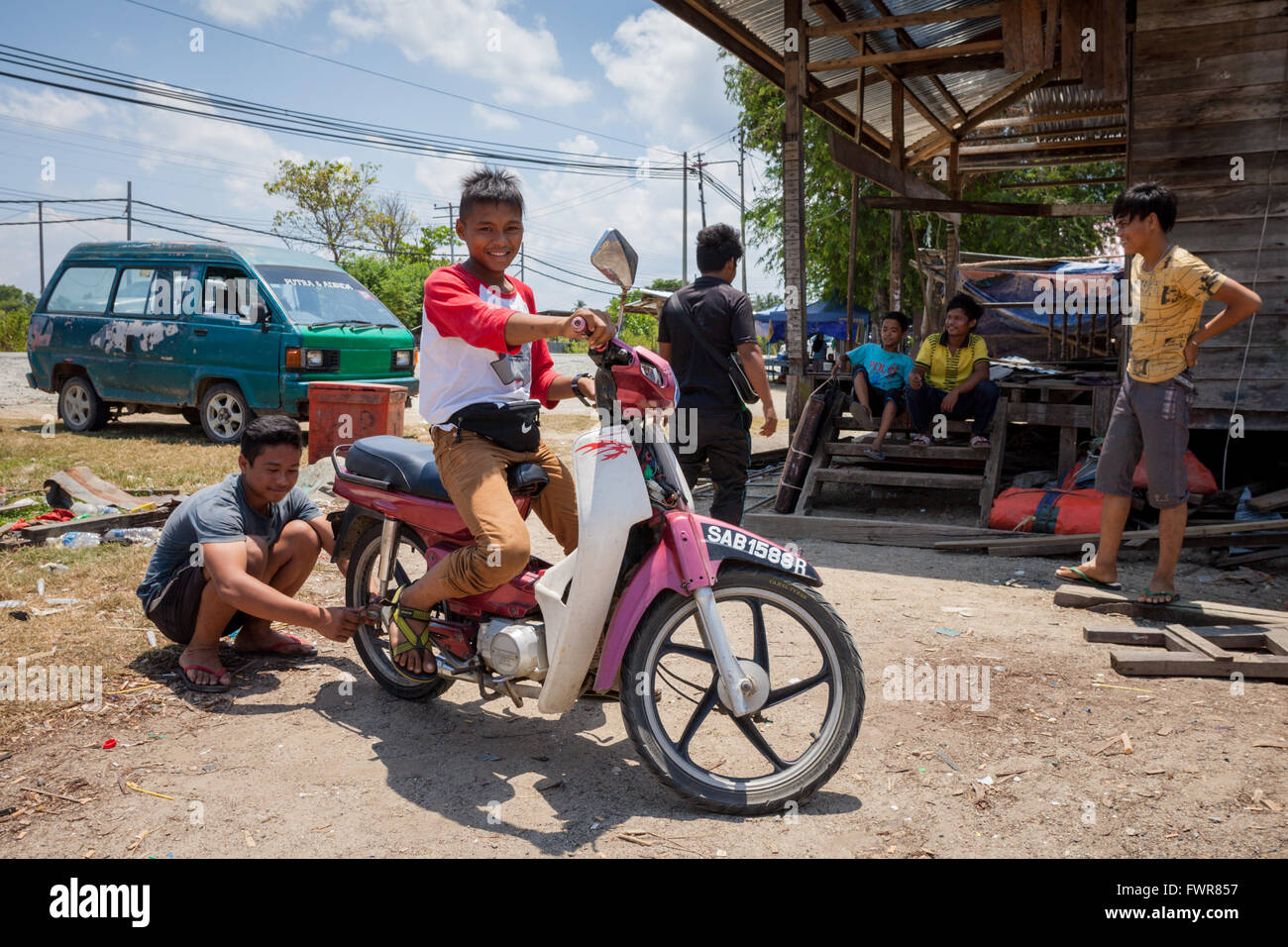 Ragazzi giovani o su una moto in un remoto villaggio nella zona pitas di Sabah, BORNEO Foto Stock